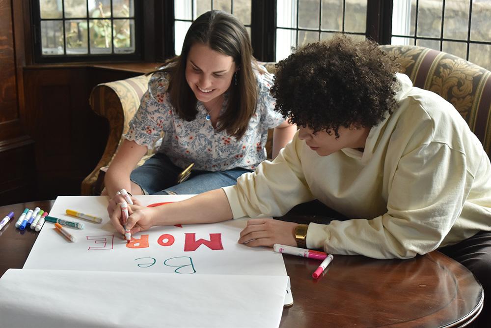 Two students drawing on a poster