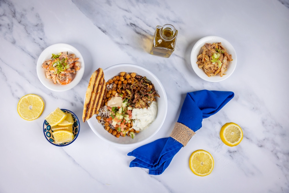 Shrimp and rice dishes over a marble countertop with blue napkins.