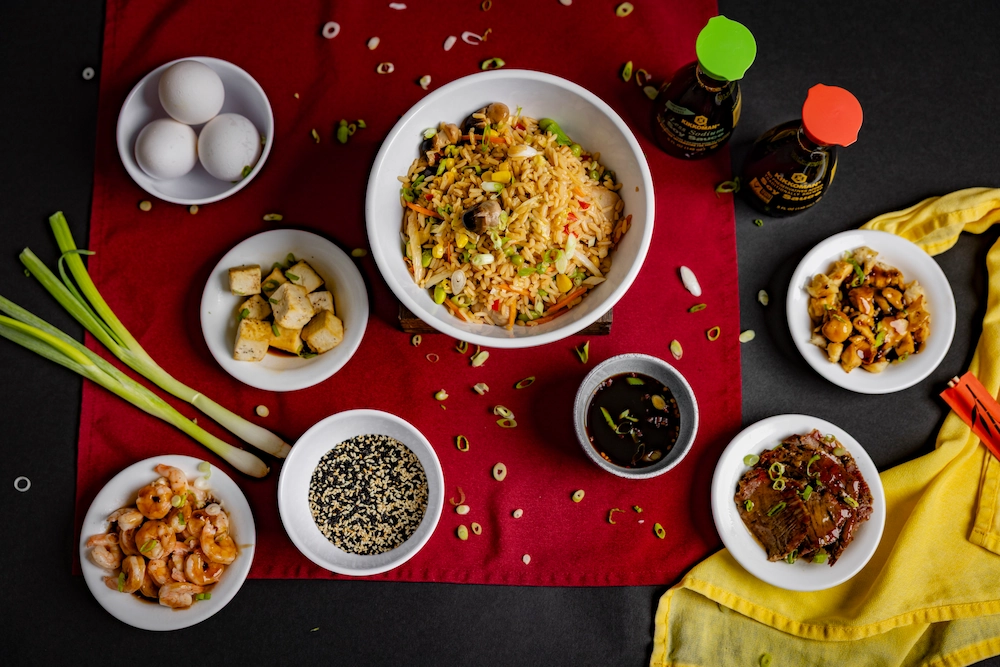 An assortment of Asian food dishes over a red table mat.