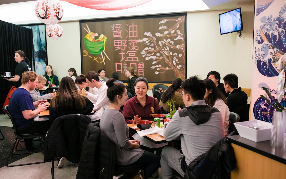 A group of students eating at a BC Dining ramen pop-up event.