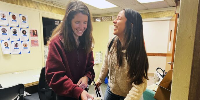 two 1Ls laughing receiveng their survival kits