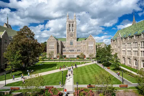 View of Gasson Hall at Boston College with students walking across the main quad on a sunny day.