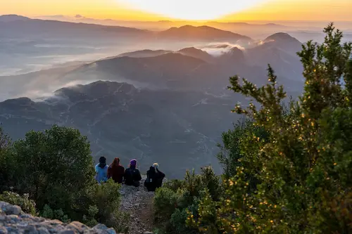 students sitting together on a mountain at sunset during capstone pilgrimage program