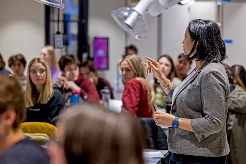 Educator speaking to a group of Boston College students in a classroom