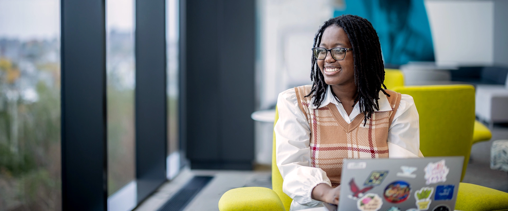 Messina College student Truns-Winslie Paul ’26 sitting with her laptop at her internship at Mass General Brigham.