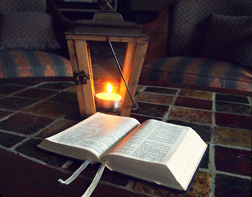 A lantern with a Bible sitting on a tile-topped coffee table.