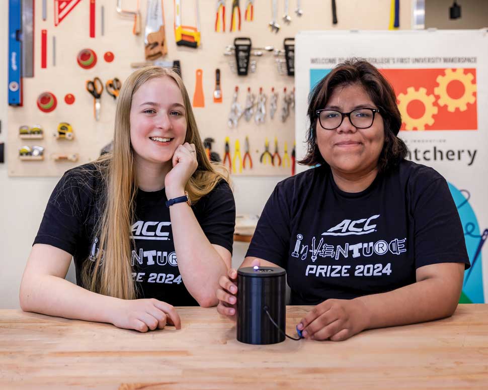 Melanie Cotta and Echo Panana photographed in the Hatchery maker space with Hue, a device they invented that identifies colors  for the visually impaired.