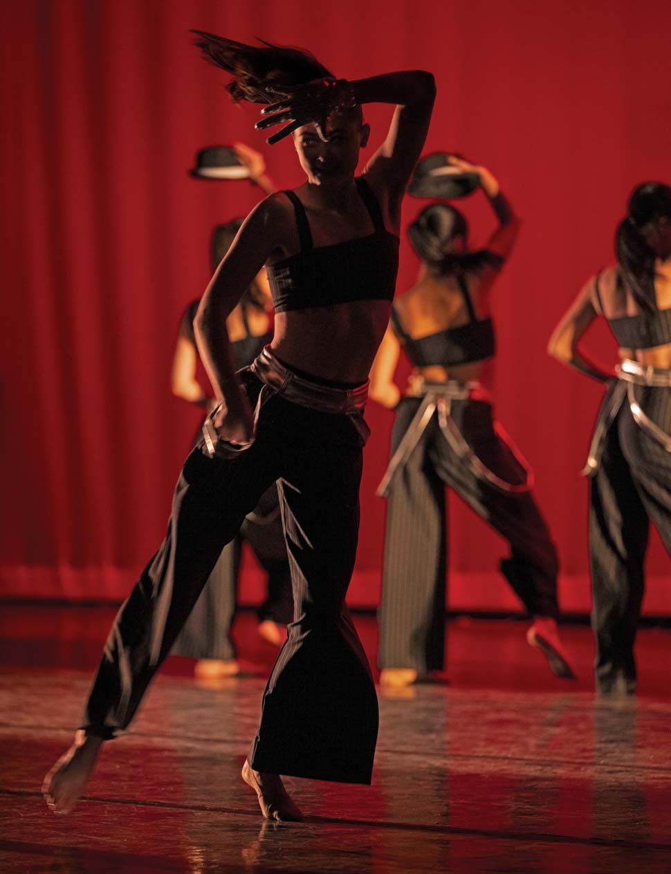 Photo of dancer in silohuette with three dancers in the background