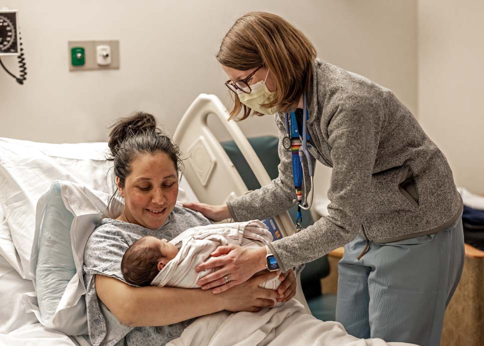 Photo of a midwife with a mother and child in a hospital environement