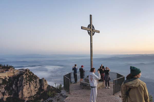 View of Montserrat with students below a cross and horizon line in distant background 