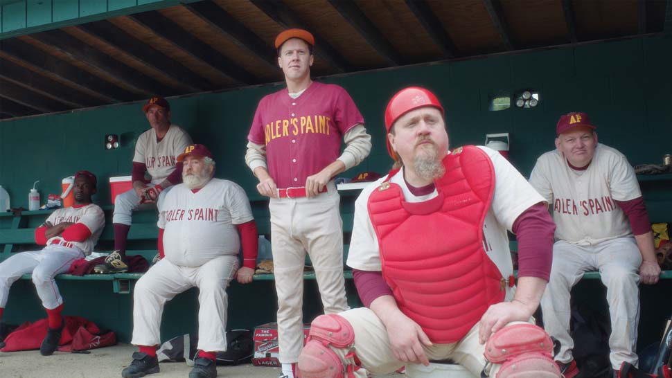 Film still of baseball players looking out from a dugout