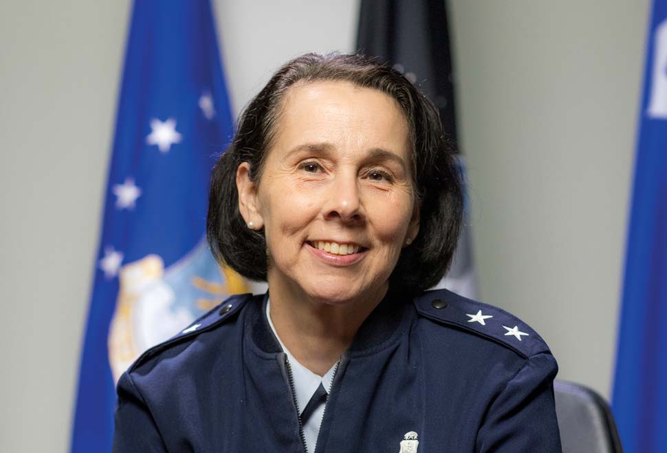 Ryder photographed at a conference table with flags in the background