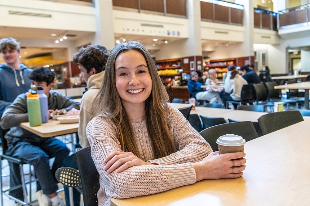 Audrey Smallwood sitting in the dining hall with a cup of coffee