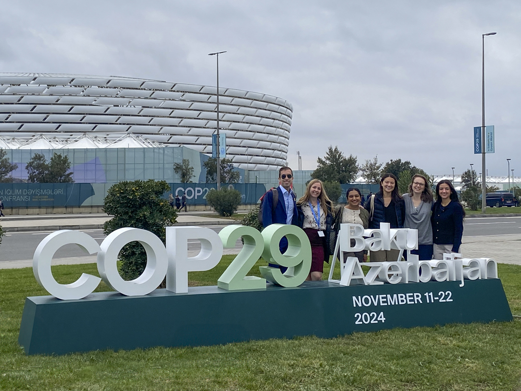 a group of students in front of COP29 signage
