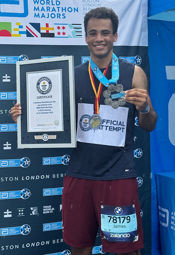 James Redding holding his medal and world record at the finish line