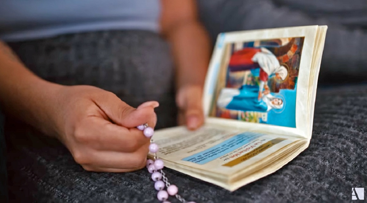 hands holding rosary and prayer book
