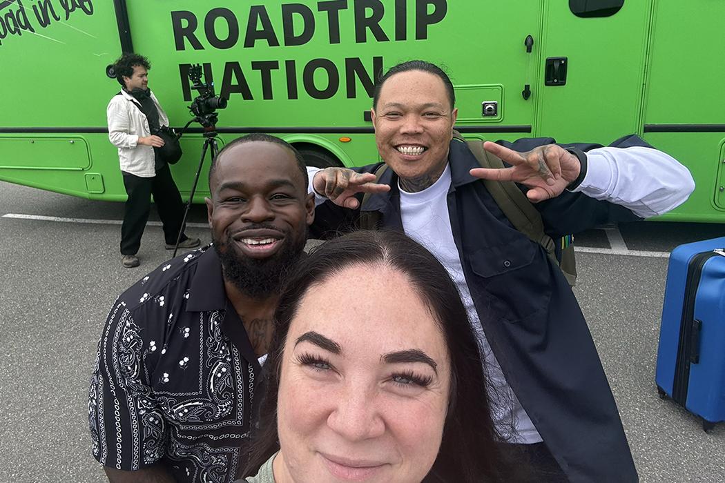 A man standing on top of an RV with palm trees in the background